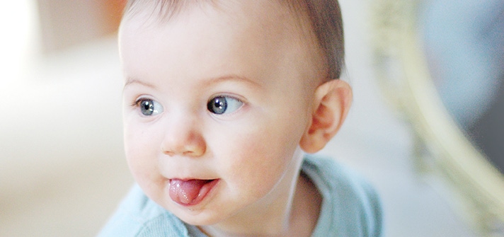 Bebé de ojos azules sacando la lengua