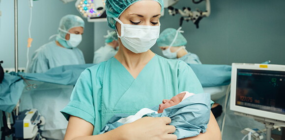 Enfermera alzando al bebé luego del parto inducido. 